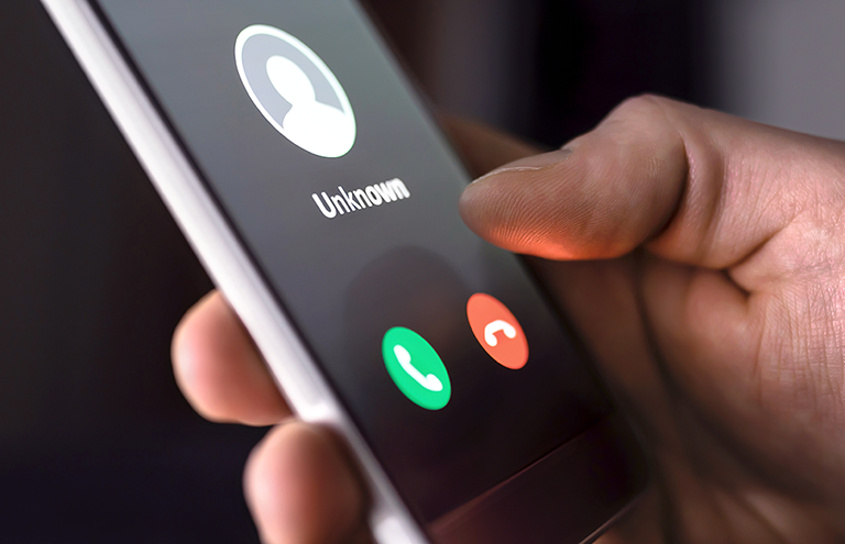 Hand holding a cell phone displaying an unknown caller.